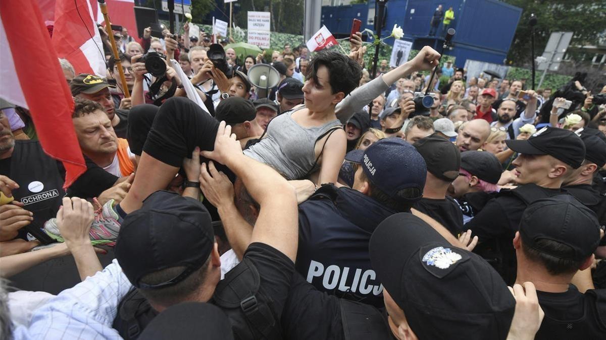 Un grupo de personas intentan romper la barrera formada por la policia durante una protesta en Polonia.