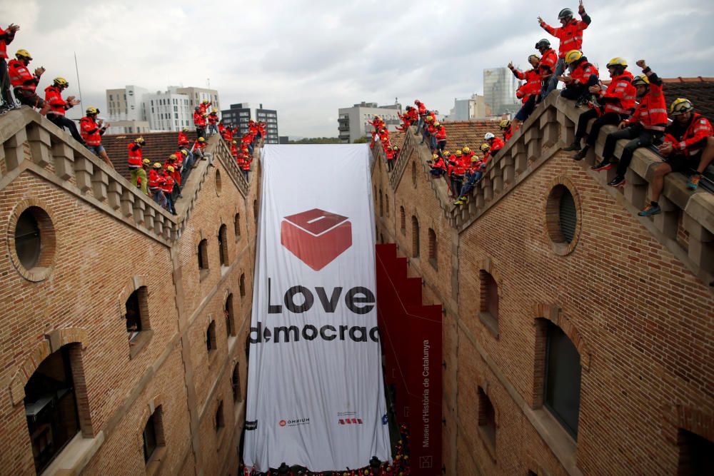 Firemen react as they hang a huge banner in ...