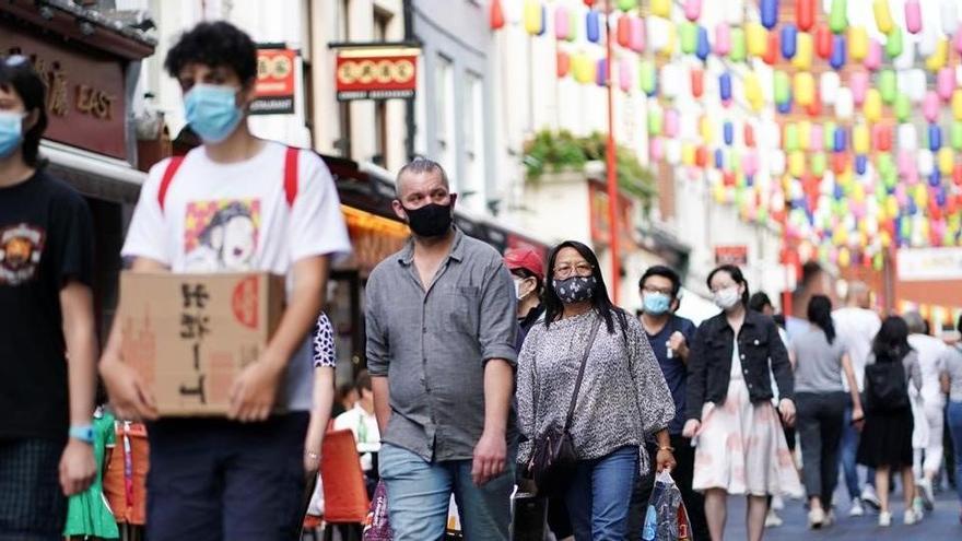 Ciudadanos con mascarilla caminan por el barrio chino de Londres.