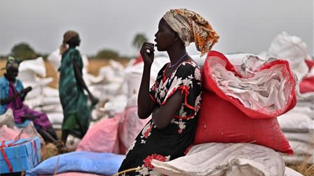 Una mujer de Sudán del Sur que se había ofrecido como voluntario para recoger raciones de alimentos en el lugar de un lanzamiento aéreo se toma un descanso.