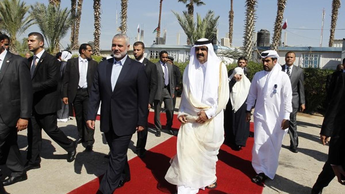 El primer ministro de Hamas, Ismail Haniyeh, camina junto al emir de Catar, Sheik Hamad bin Khalifa al-Thani, por una alfombra roja.