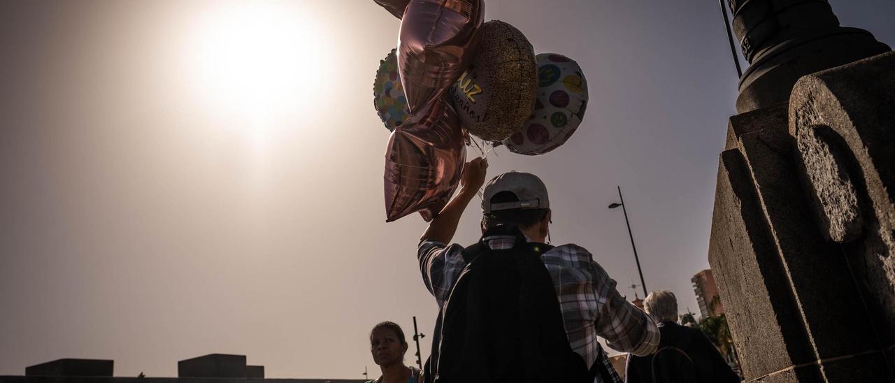 Un hombre pasea con globos bajo la calima en Santa Cruz.