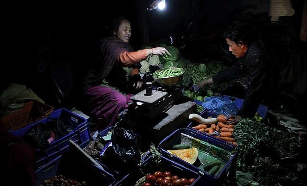 Una dona ven verdures gairebé en la foscor pels freqüents talls elèctrics a Kàtmandu, Nepal. El subministrament d’energia al país s’ha tallat durant 12 hores cada dia a causa dels baixos nivells als dipòsits que alimenten les centrals hidroelèctriques del país.