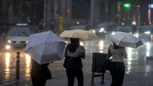 Dues persones sota la pluja, en una imatge d&amp;apos;arxiu