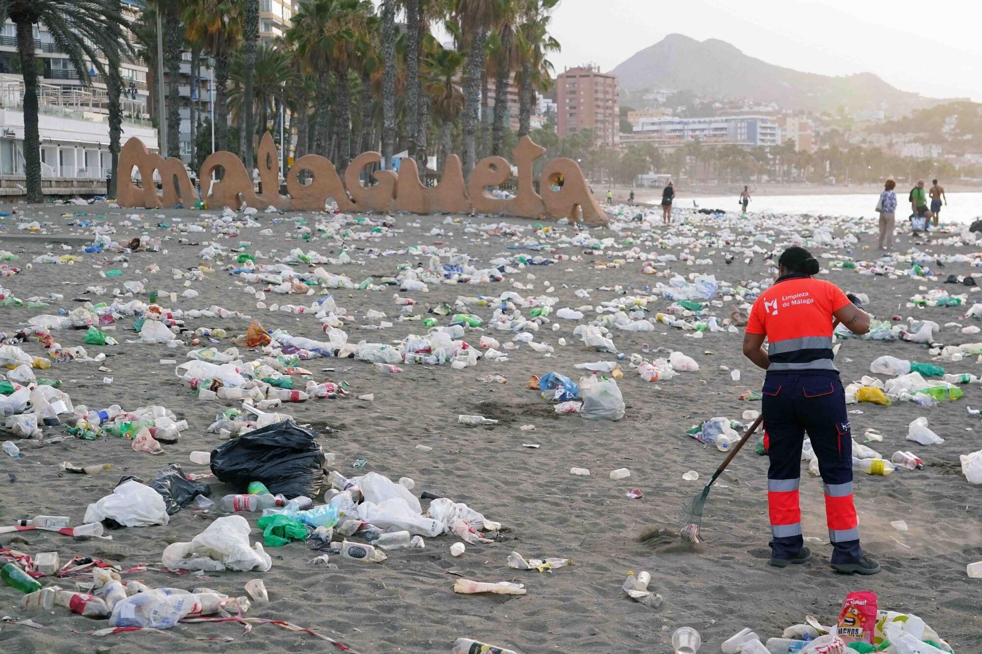 Varios operarios de la empresa de limpieza de Limasam, recogen los residuos de la playa de La Malagueta, tras la Noche de San Juan en Málaga 2025