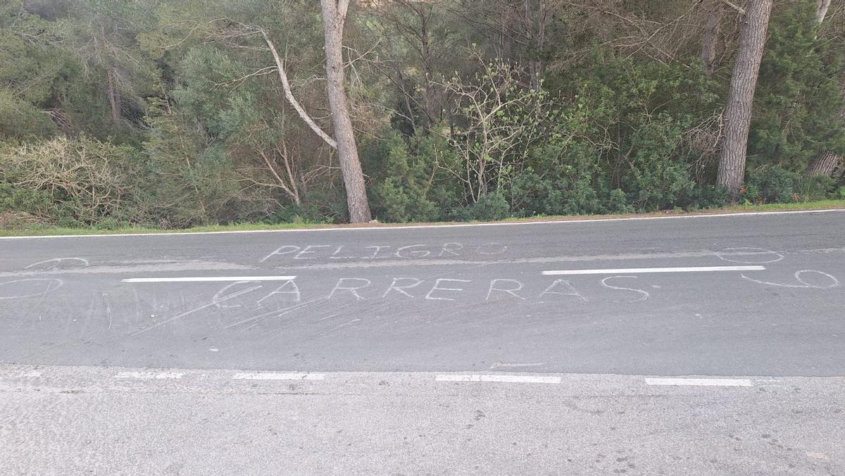 Aviso en el asfalto: «Peligro, carreras» .