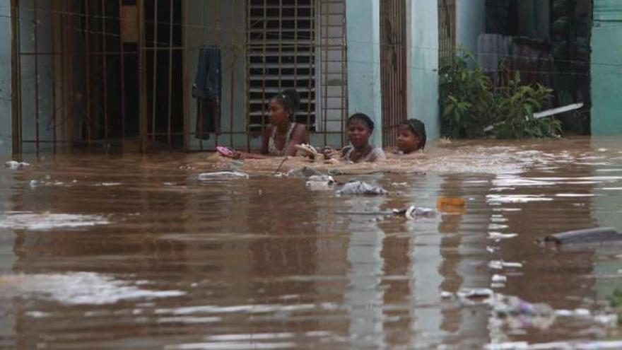 Tres mujeres en una calle inundada de San Cristóbal (República Dominicana), tras el paso del &#039;Irene&#039;. / o. barría