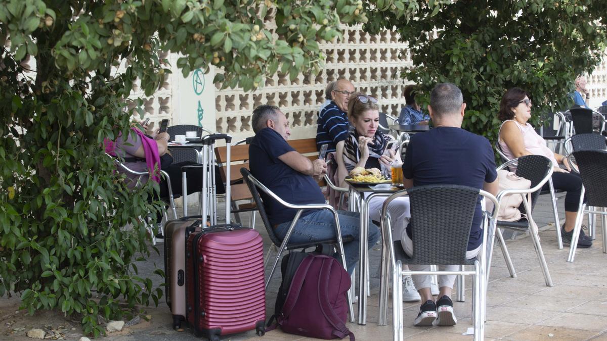 Turistas con sus maletas tomando un aperitivo en una terraza de Alicante este lunes
