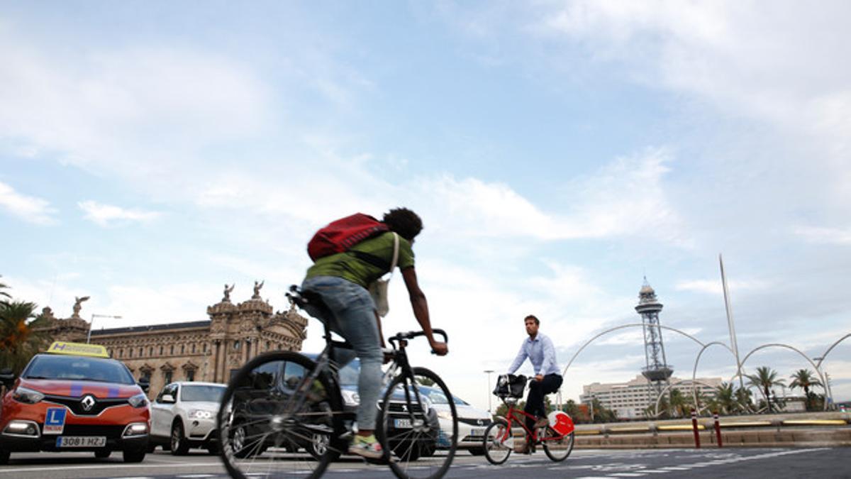 Una bicicleta se cruza con un conche en la Plaça de les Drassanes de Barcelona.