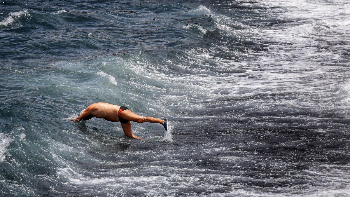 Un hombre se da un chapuzón en la playa.