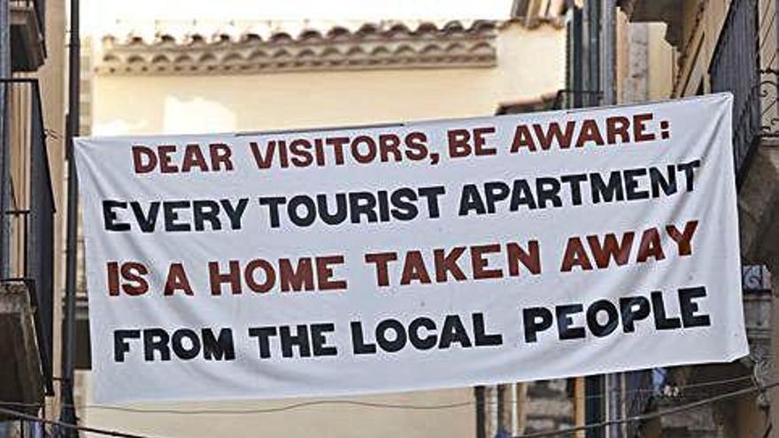 Una pancarta contra els pisos turístics al carrer Mercader de Girona.