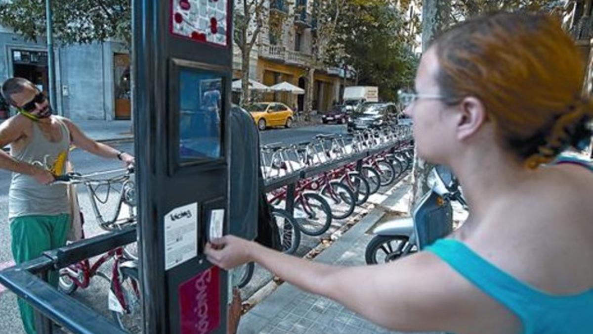 Una usuaria coge una bicicleta en una estación de la calle de Casp, donde un anuncio alerta del corte que empieza hoy.