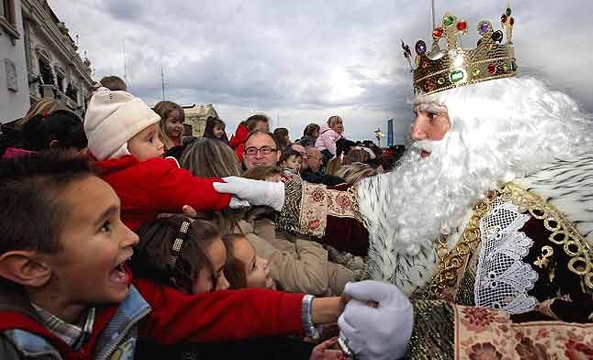 El rei Melcior saluda els nombrosos nens que es van acostar fins al port per rebre els tres Reis Mags a l’arribar a la ciutat de València.