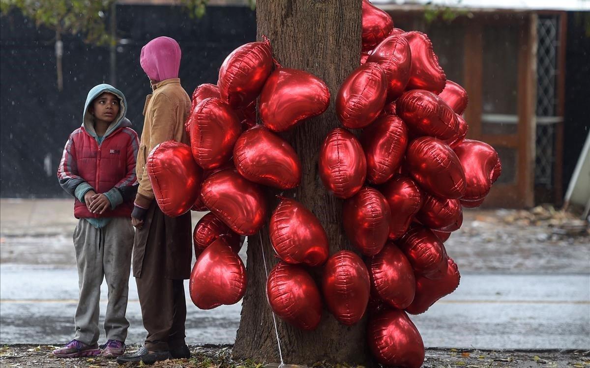 Jóvenes vendedores pakistaníes junto a globos con forma de corazón esperan clientes en el Día de San Valentín en una carretera de Islamabad, Pakistán.