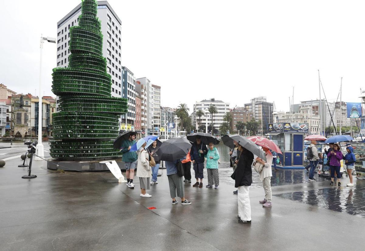 Fotografía de archivo de turistas bajo la lluvia en Gijón.