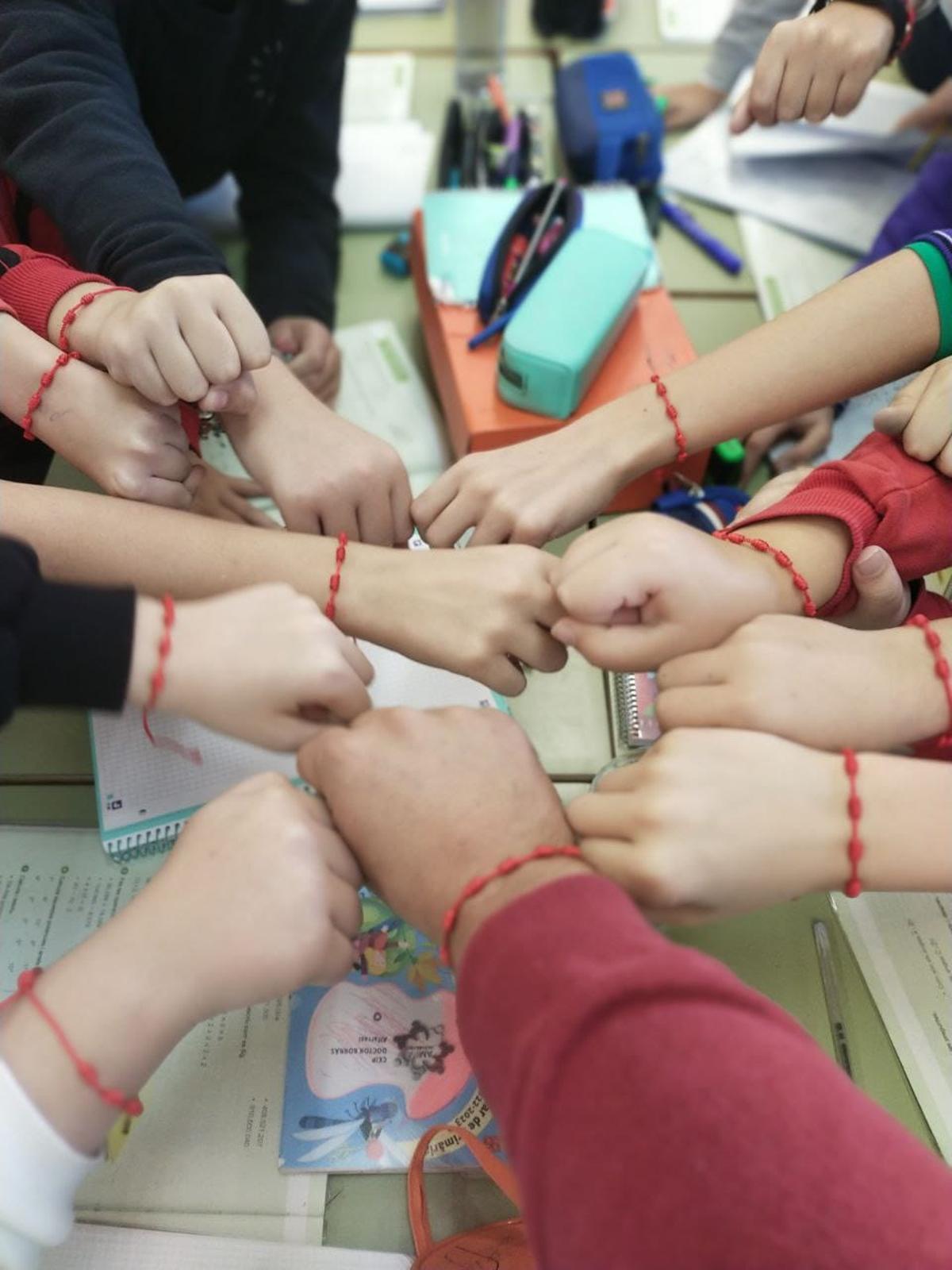 Alumnos del colegio muestran sus pulseras rojas.