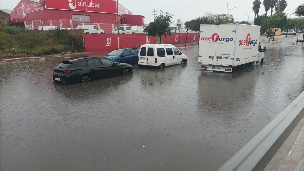 Coches atravesando la balsa de agua en la calle César Vallejo, del polígono Guadalhorce.