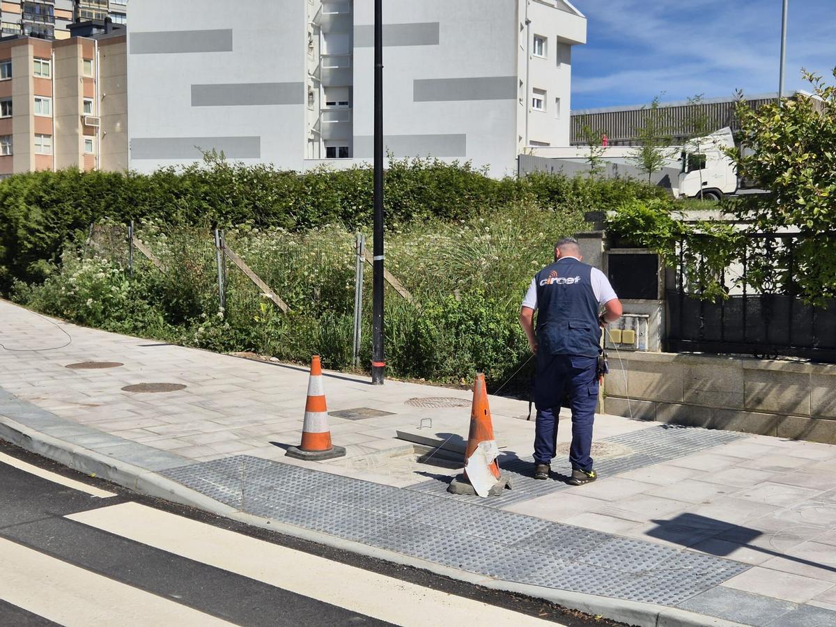 Un operario tira la nueva línea de fibra óptica por la canalización de la rúa Sauces.