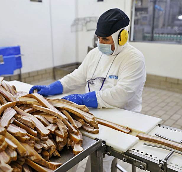 El trabajador Enrique Granja preparando panceta para su corte Los operarios | Marcos León