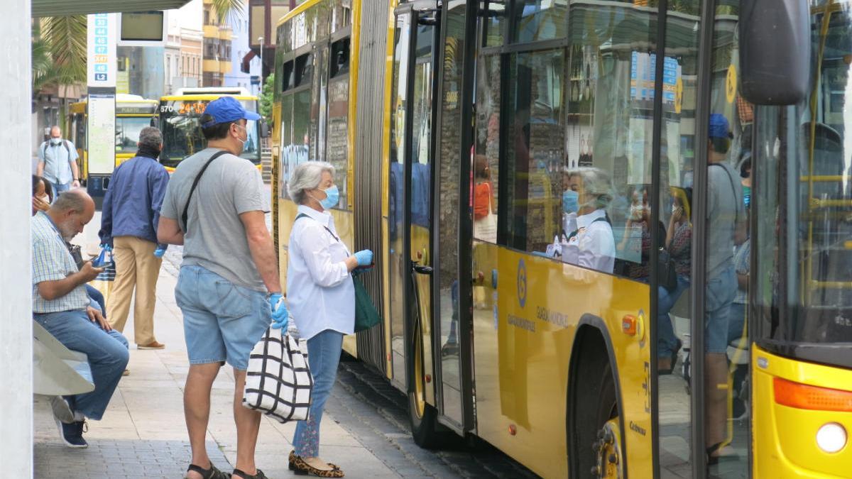 Viajeros con mascarilla en una parada de Guaguas