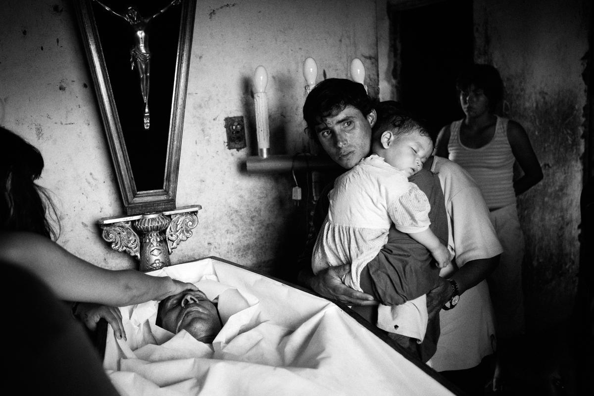 ’Orilleros’. Miguel Machado y su hijo, durante el funeral de su padre. Antonio se ahogó en su propio vómito después de una noche de alcohol. El alcoholismo es muy común entre los hombres de estas comunidades que habitan cerca del río Paraná.