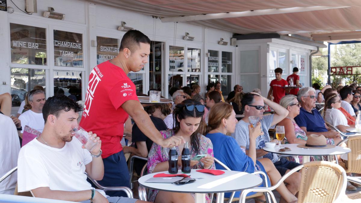 Un cambrer servint una taula a un bar de primera línia de platja a Cadaqués.