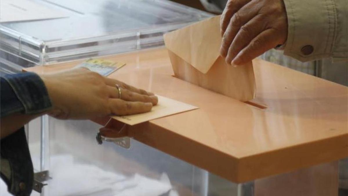 Una persona deposita su voto en la urna.