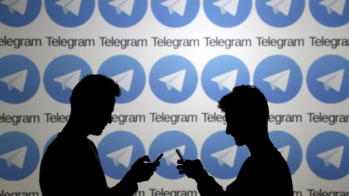Usuarios consultan sus móviles junto a un panel de Telegram. 