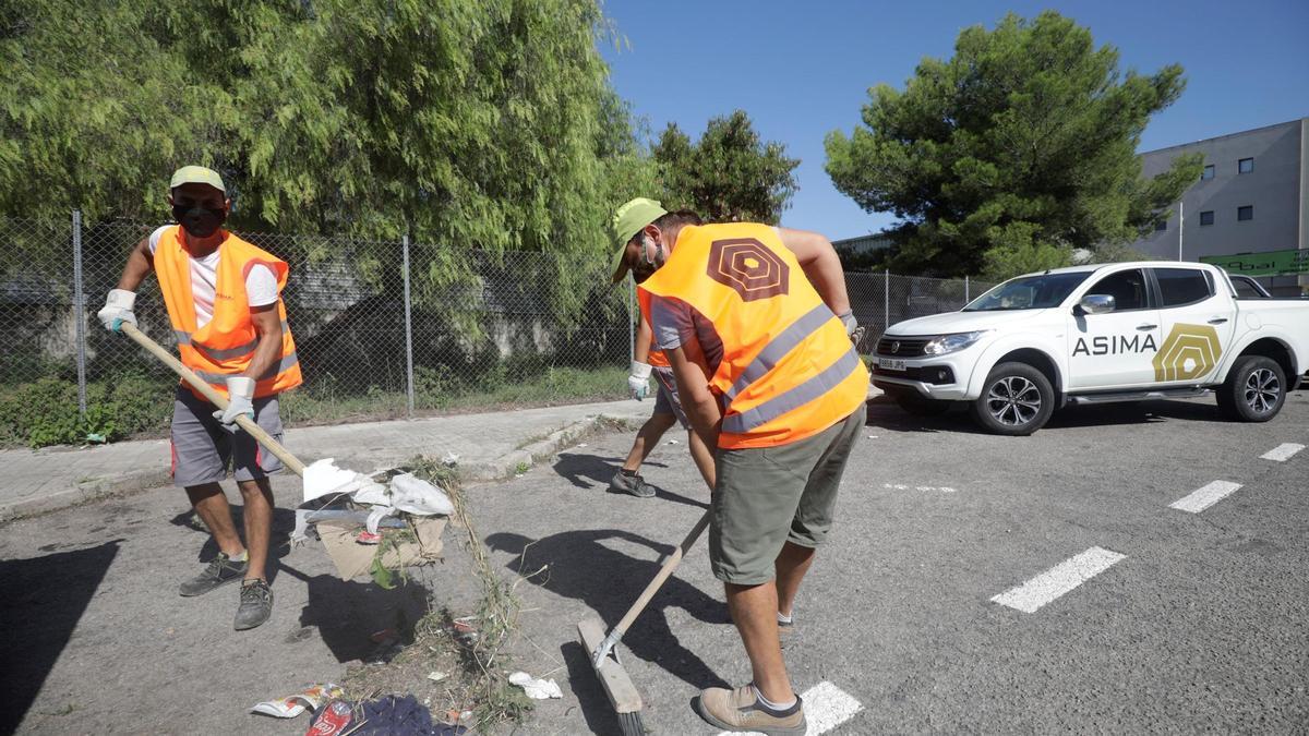 Dos operarios amontonan suciedad