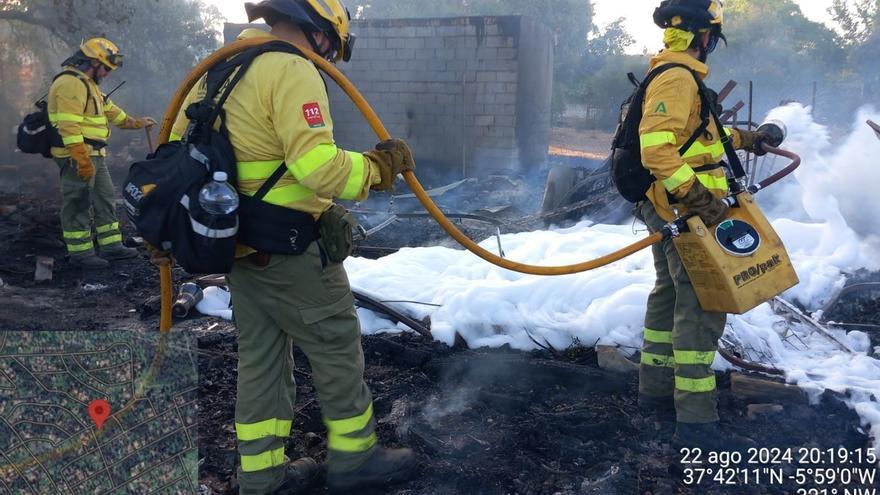 Bomberos del Plan Infoca apagan las llamas en el interior de una parcela de la urbanización La Mina, en Castilblanco de los Arroyos (Sevilla).