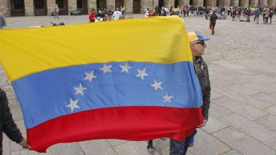Dos manifestantes sostienen una bandera de Venezuela, ayer, en el Obradoiro.  // Xoán Álvarez