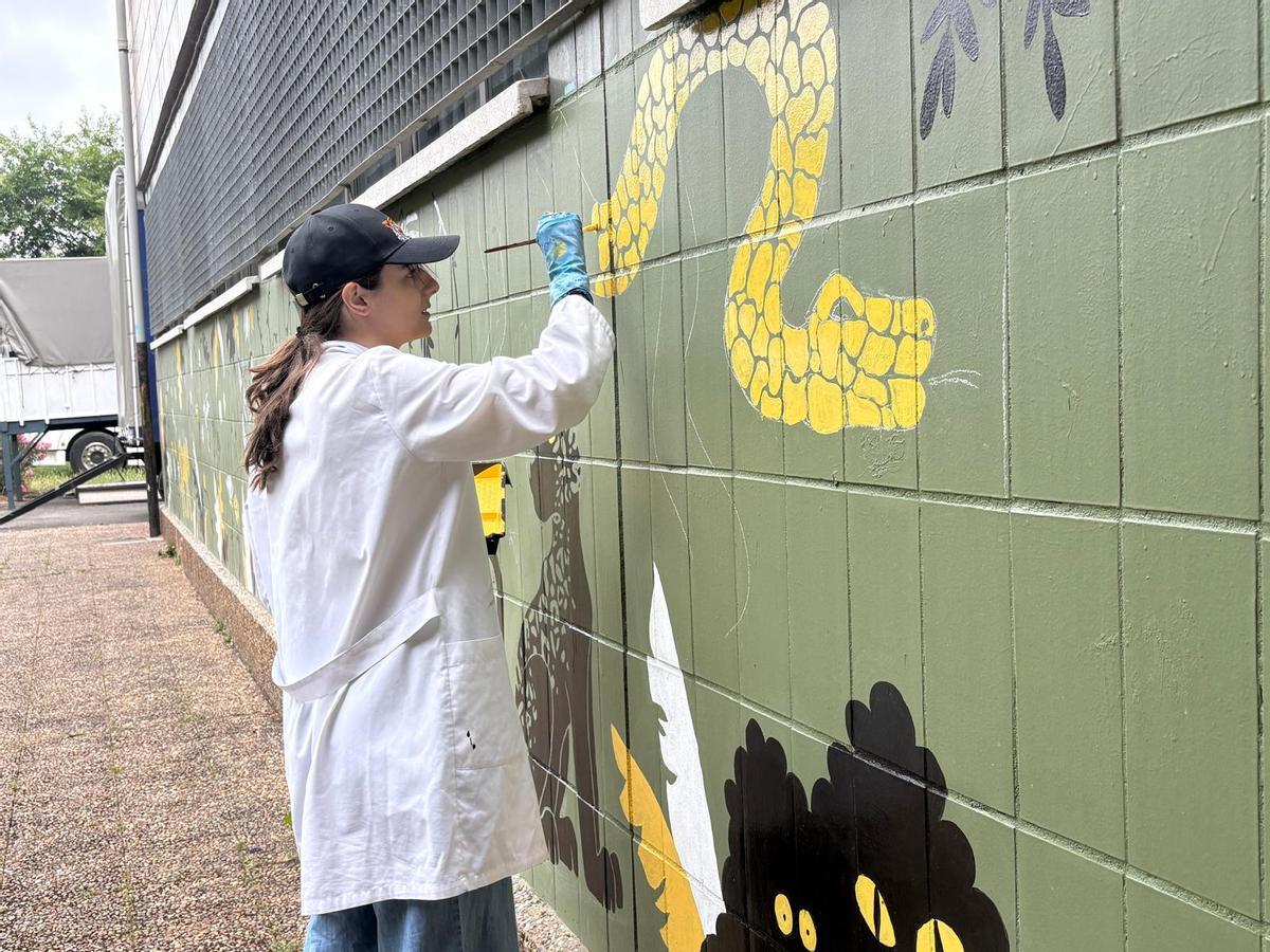 María Murias pinta la serpiente en el mural.