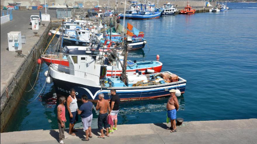 Un grupo de personas charla sobre la situación del sector frente a todos los barcos de la flota de la cofradía de pescadores de Arguineguín.