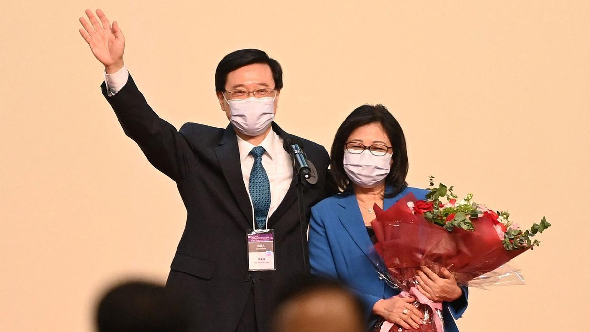 John Lee (L) and his wife Janet (R) celebrate after Lee was named as the city's new leader in Hong Kong on May 8, 2022. - John Lee, the former security chief who oversaw the crackdown on Hong Kong's democracy movement, was declared the business hub's new leader on May 8, 2022 by a small committee of Beijing loyalists. (Photo by Peter PARKS / AFP)