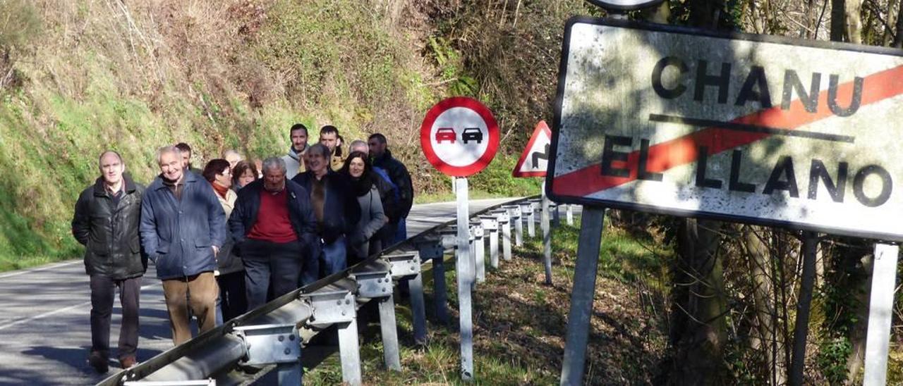 Vecinos de El Llano y Santa Eulalia caminan por el arcén de la carretera a la entrada del pueblo.