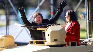 El presidente de Argentina, Javier Milei, hace gestos desde un vehículo militar junto a la vicepresidenta Victoria Villarruel, durante un desfile militar.