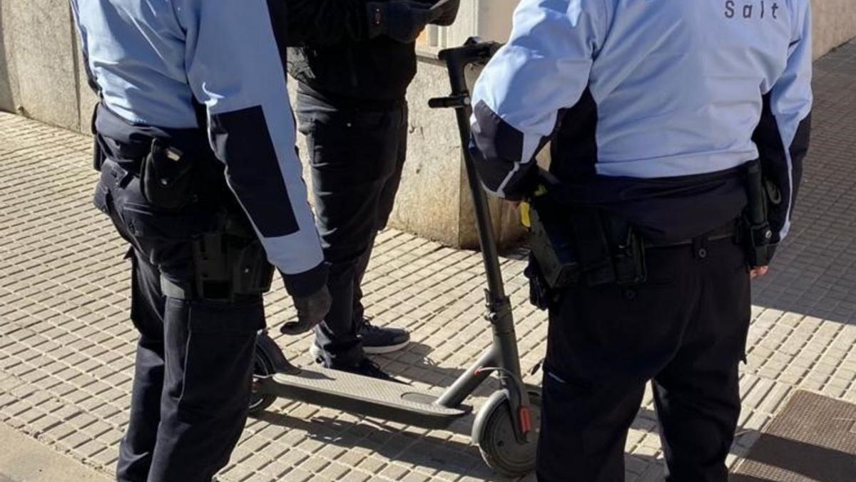 Dos agents de la Policia de Salt amb un usuari de patinet elèctric en una imatge d’arxiu.