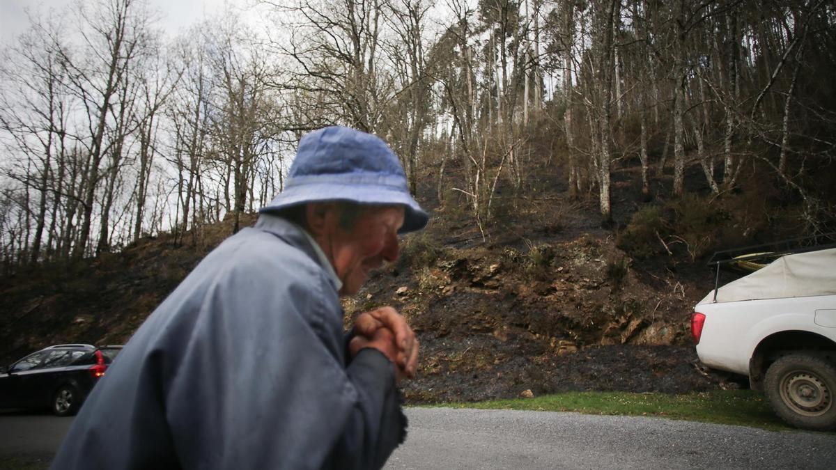 Un hombre camina junto al monte quemado por un incendio forestal, a 30 de marzo de 2023, en Baleira