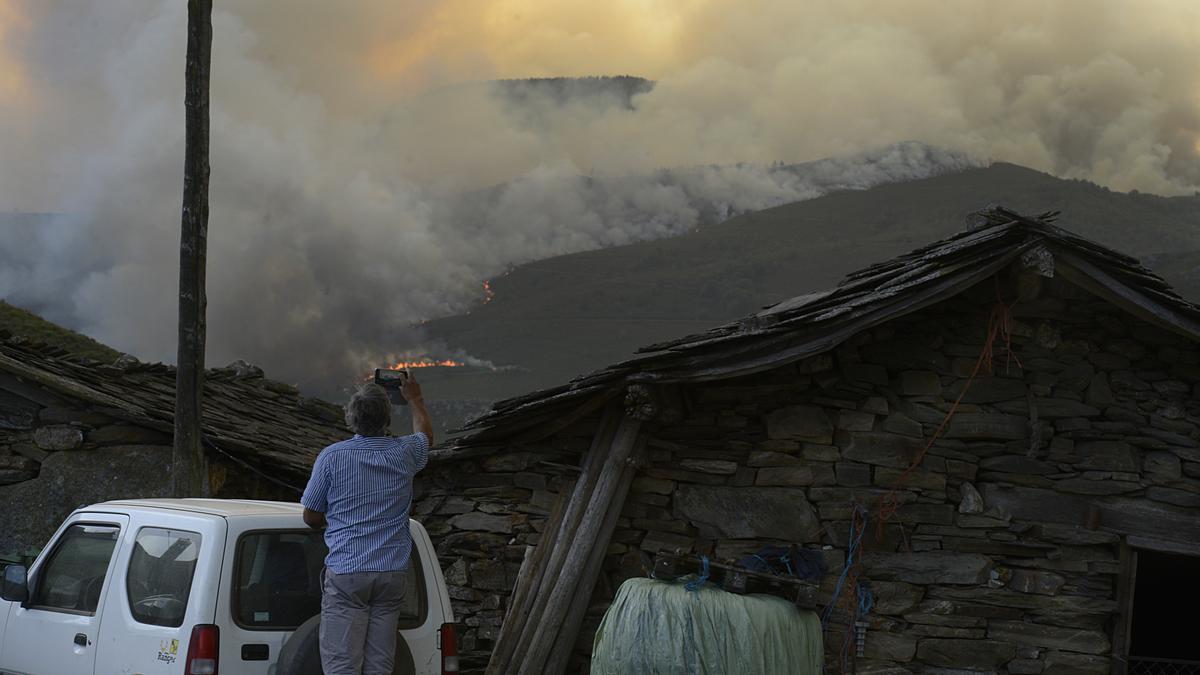 Un hombre toma fotografías de las llamas del incendio de Laza.