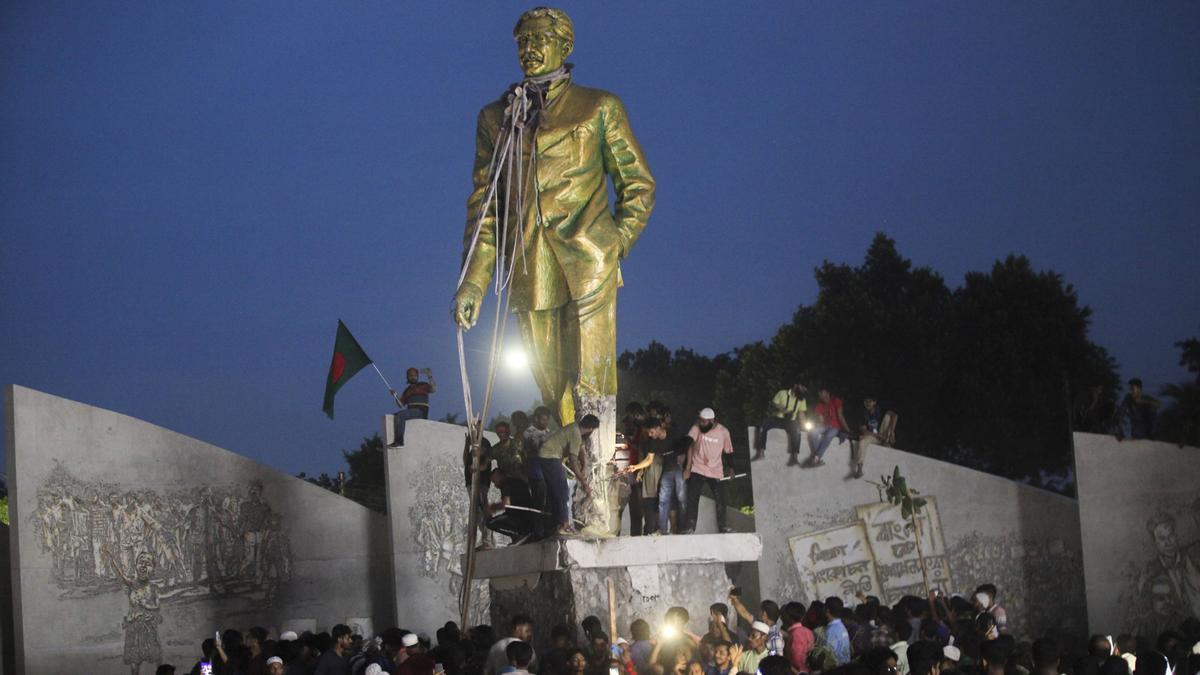 Estudiantes encaramados a una estatua de Sheij Mujibur Rahman, fundador de Bangladesh y padre de Sheij Hasina.