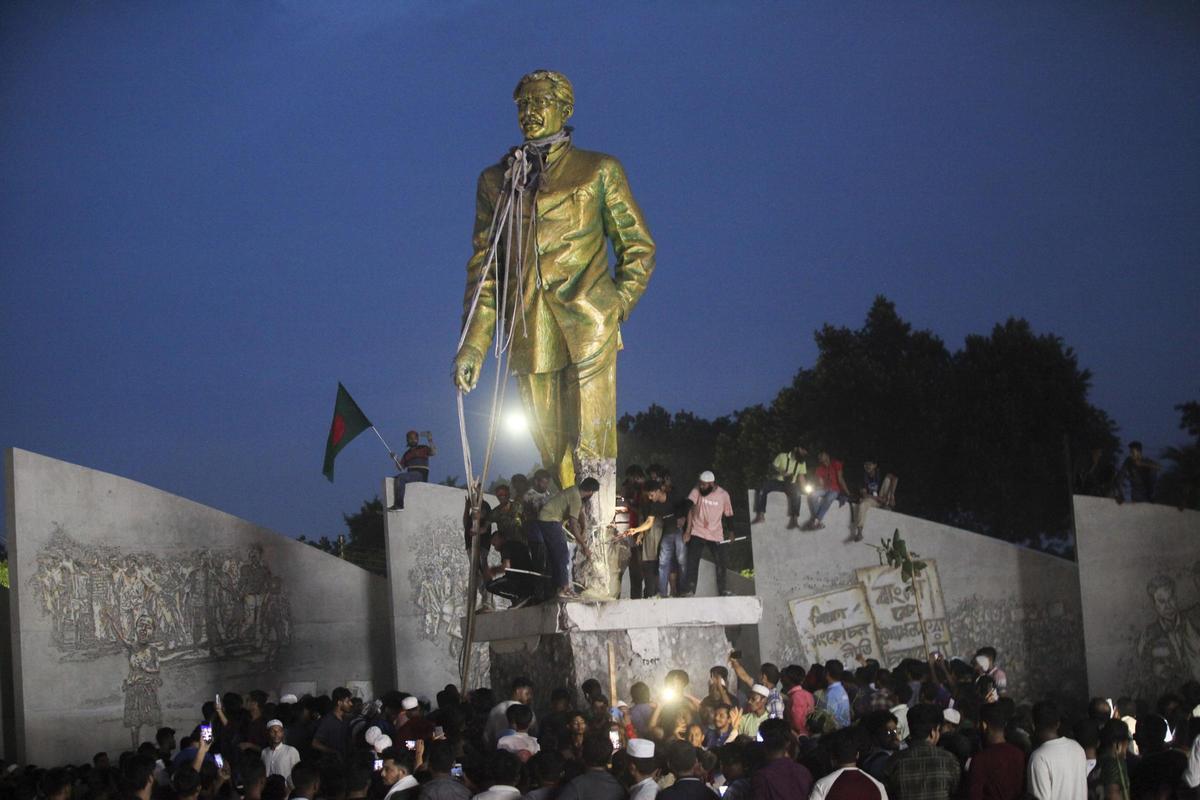 Estudiantes encaramados a una estatua de Sheij Mujibur Rahman, fundador de Bangladesh y padre de Sheij Hasina.