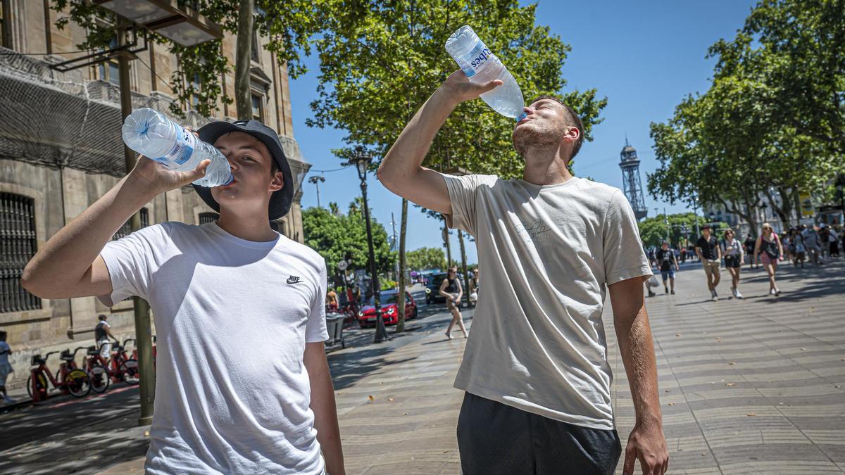 Dos turistas se refrescan en las Ramblas en julio de 2022, durante una ola de calor.