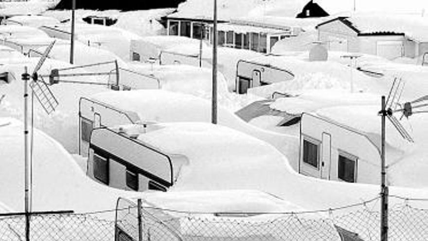 Caravanas, cubiertas por la nieve, aparcadas en el camping de La Raya.