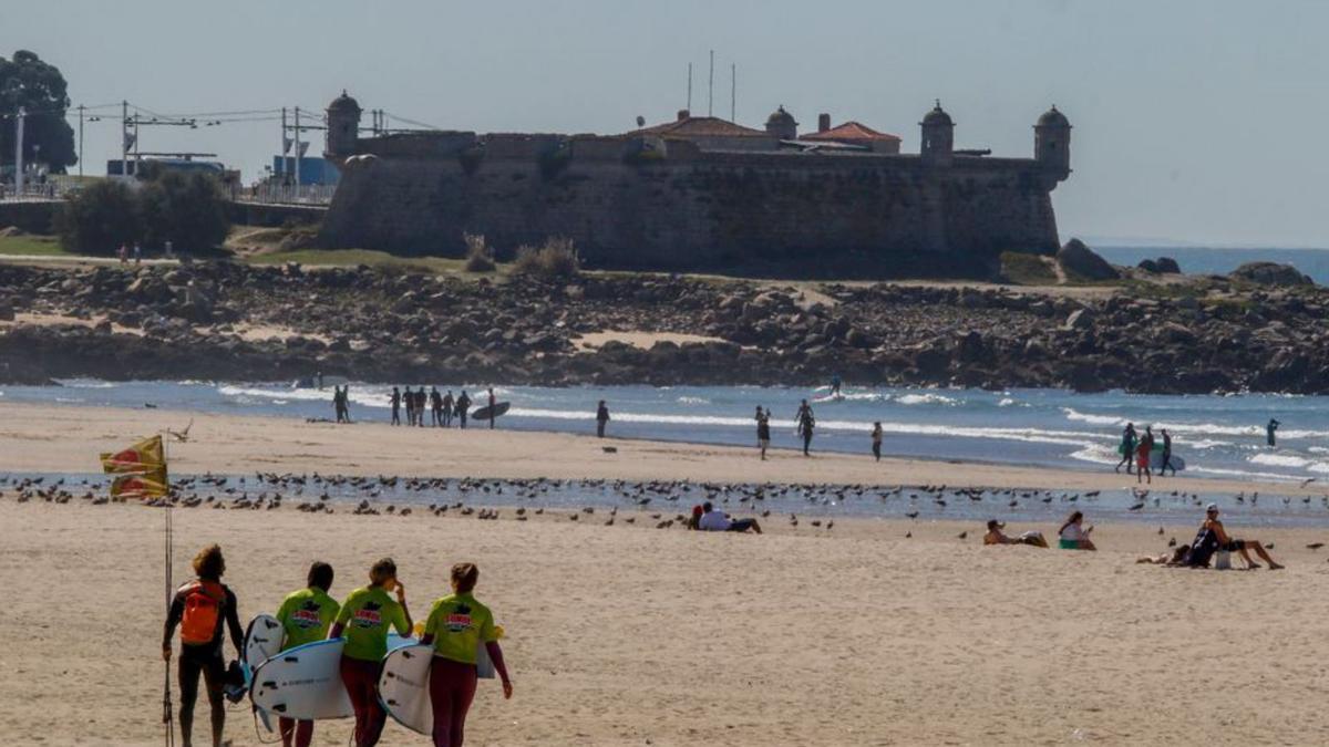 Surfistas con el Castelo do Queijo al fondo.   | // IÑAKI ABELLA