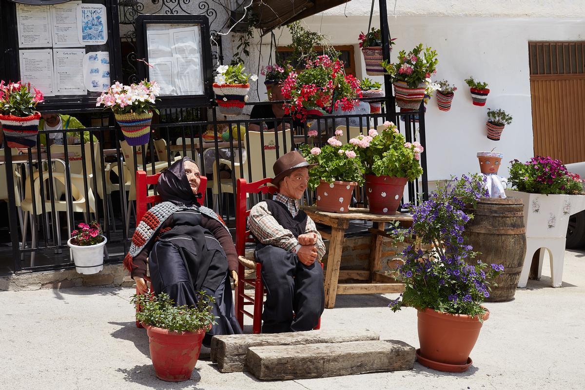 Muñecas con ropa tradicional están sentadas en la entrada de un café callejero