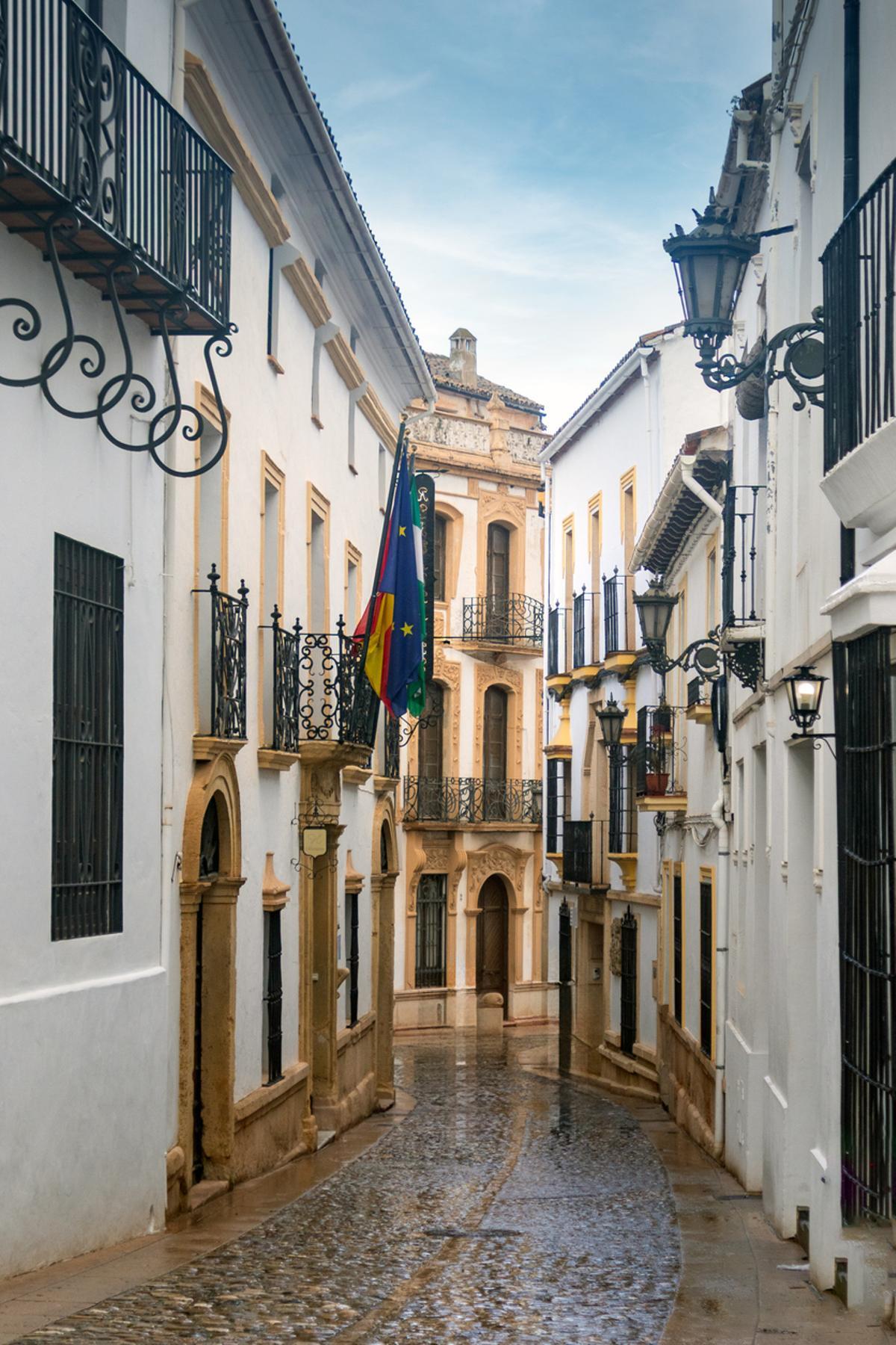 Calle estrecha de adoquines con fachadas históricas en Ronda, España