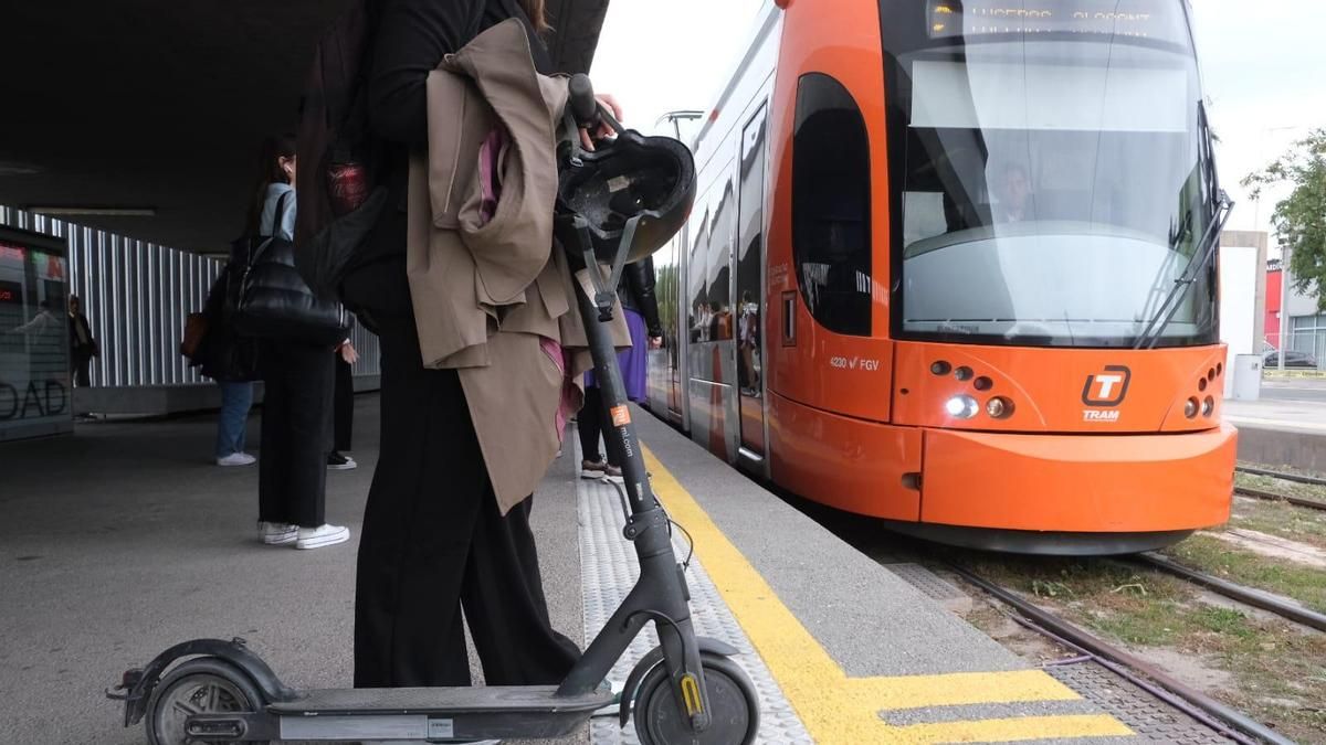 Una persona con un patinete eléctrico, a punto de subirse a un TRAM, en una imagen de archivo