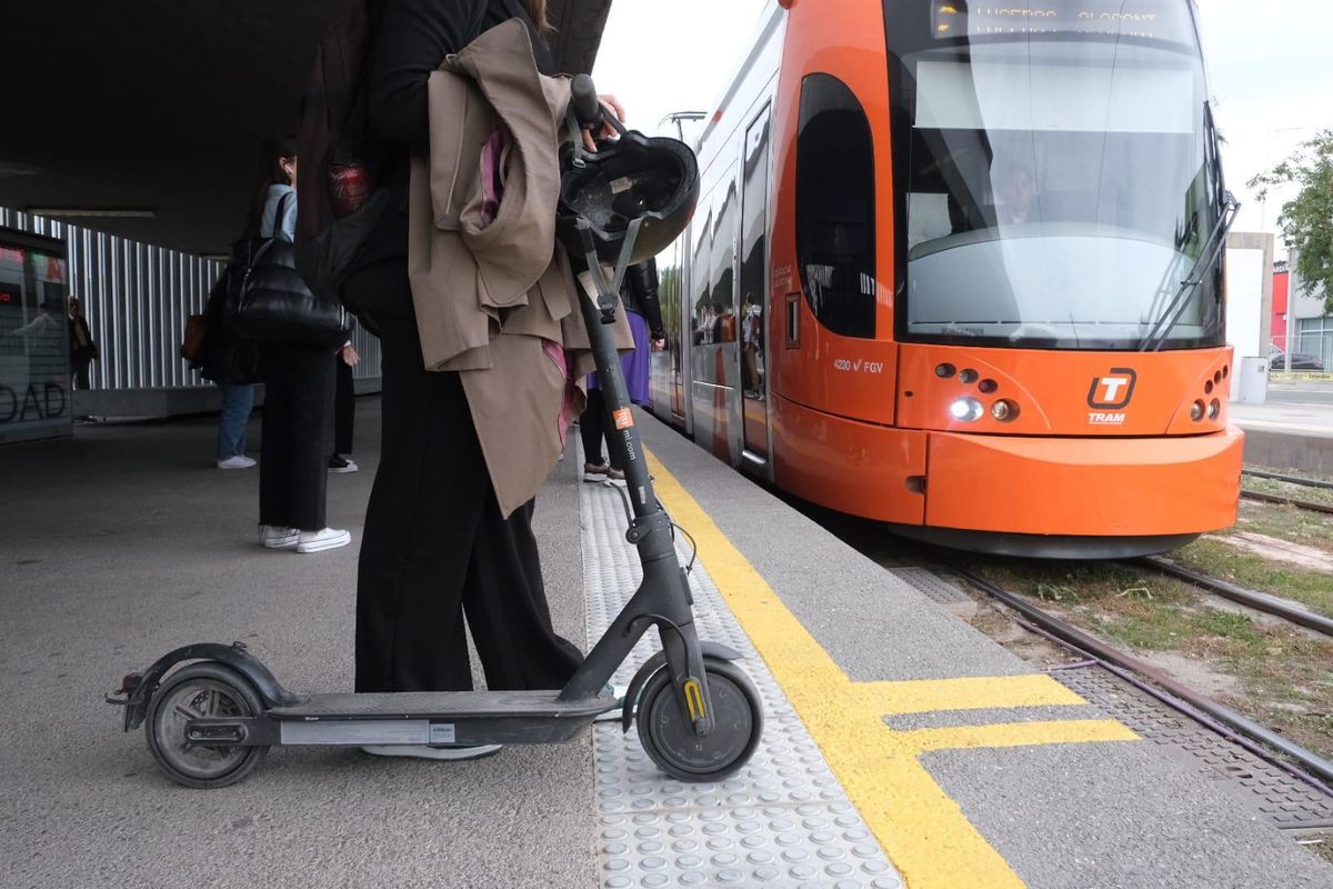 Una persona con un patinete eléctrico, a punto de subirse a un TRAM, este martes en Alicante