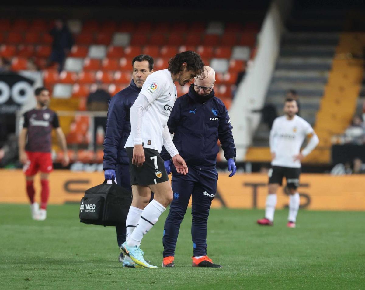 Cavani se retira del campo junto al fisioterapeuta del Valencia CF, José Baixauli.  | J.M. LÓPEZ