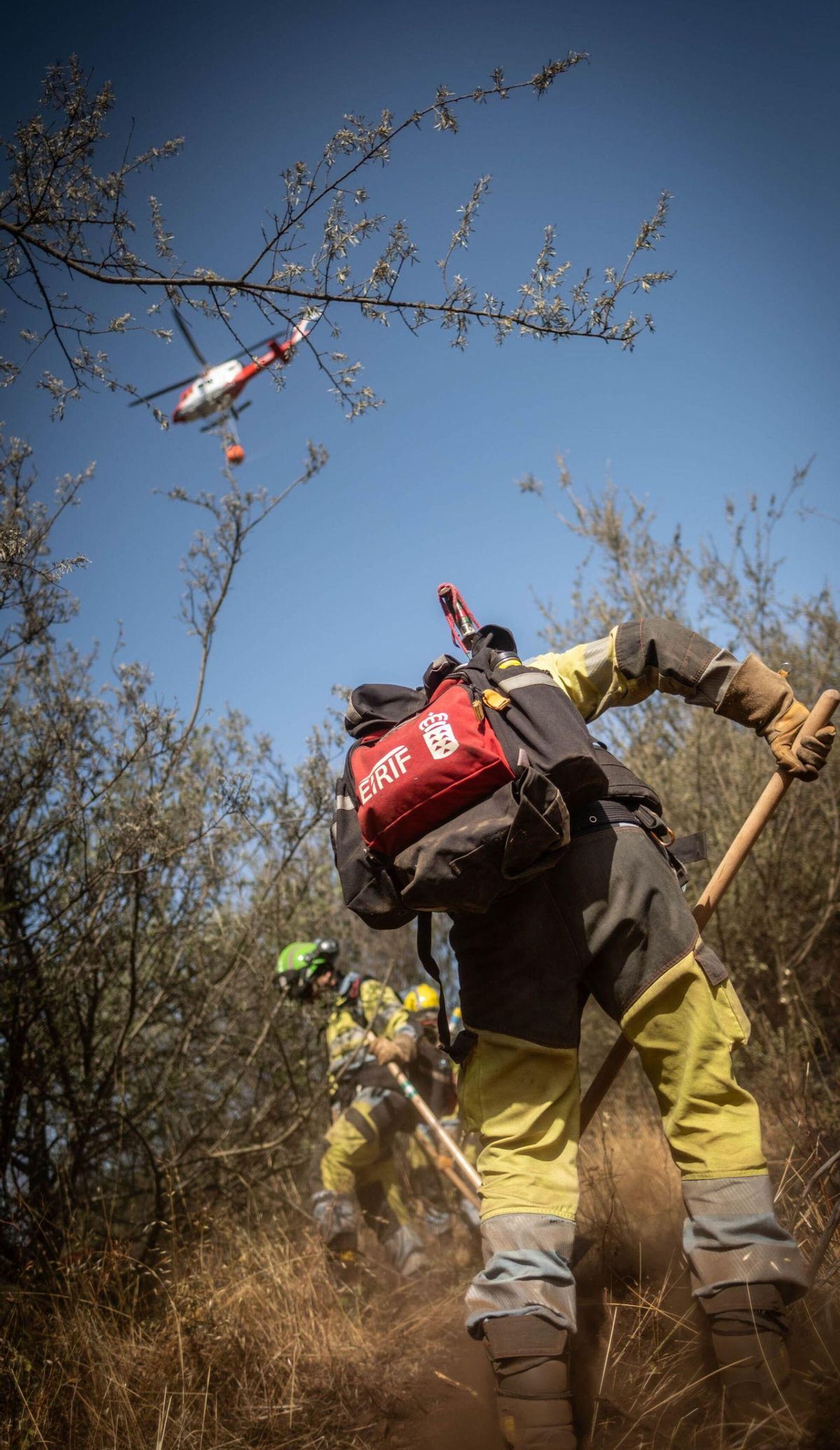 Los equipos en tierra desbrozan la maleza para impedir que el fuego se extienda. | ANDRÉS GUTIÉRREZ